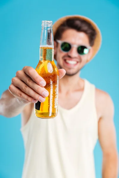 Man in hat and sunglasses giving you bottle of beer — Stock Photo, Image