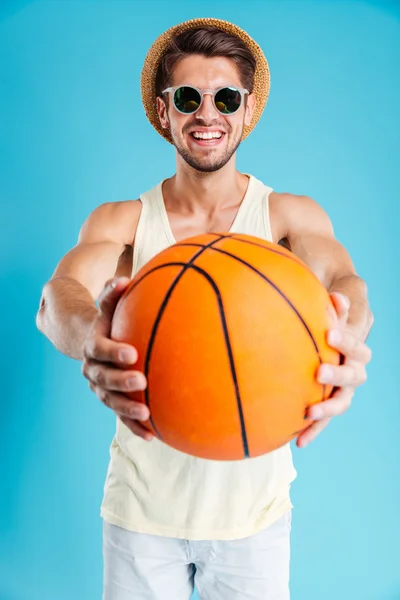 Homme heureux dans le chapeau et les lunettes de soleil vous donnant ballon de basket — Photo