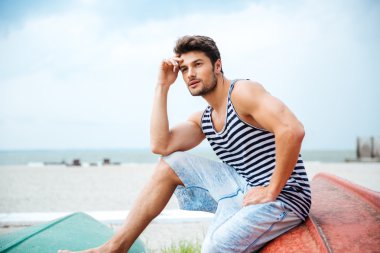 Deniz kıyısında bir balıkçı teknesinde oturan dalgın adam