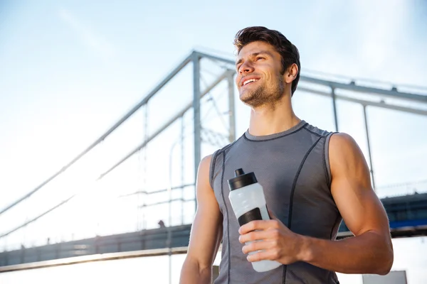 Young smiling sports man resting after running, holding water bottle — Φωτογραφία Αρχείου