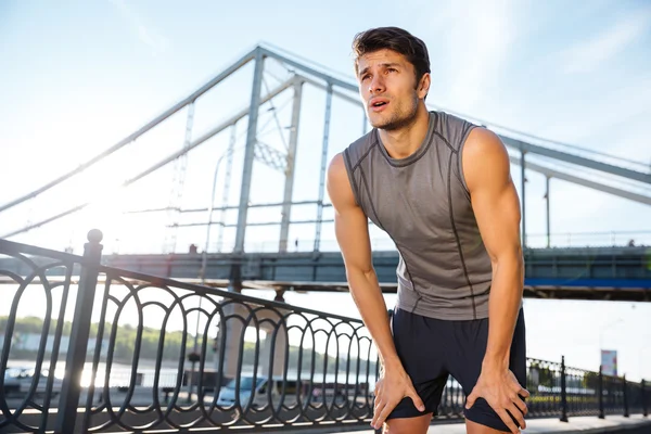 Homem de esportes descansando depois de correr em pé na ponte — Fotografia de Stock