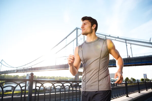 Bonito homem de esportes correndo ao longo da ponte moderna ao pôr do sol luz — Fotografia de Stock