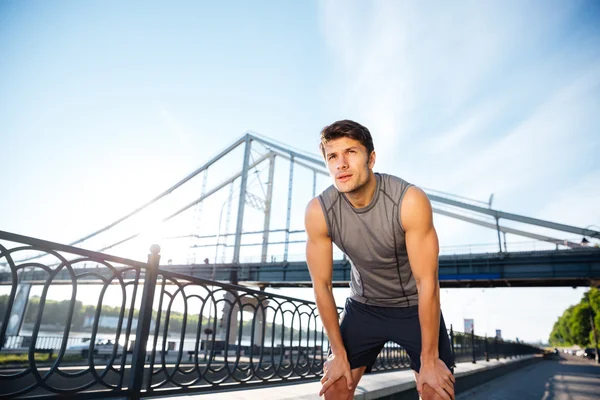 Homem de esportes descansando depois de correr em pé na ponte — Fotografia de Stock