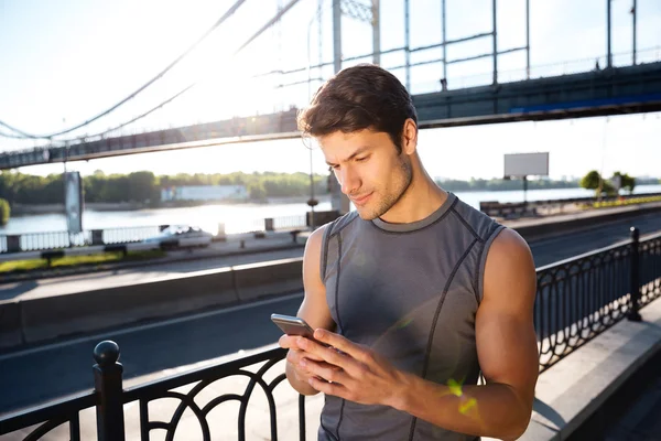 นักวิ่งใช้สมาร์ทโฟนมือถือ และยืนอยู่ที่สะพาน — ภาพถ่ายสต็อก