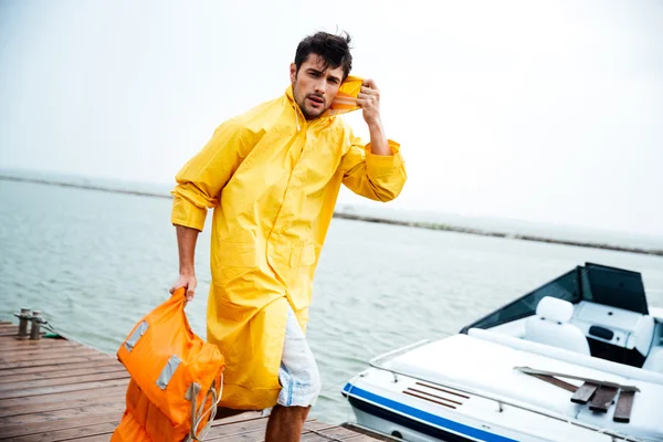 Sailor man in yellow cloak walking at the sea pier — Stock Photo, Image