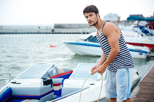 Guapo joven marinero sosteniendo la cuerda en el muelle — Foto de Stock