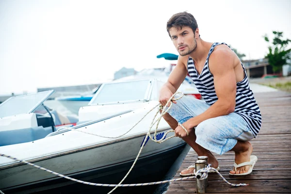 Handsome young sailor holding rope at the pier — Stock Photo, Image