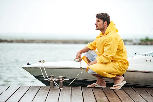 Sailor in yellow cloak holding rope at the pier — Stock Photo, Image