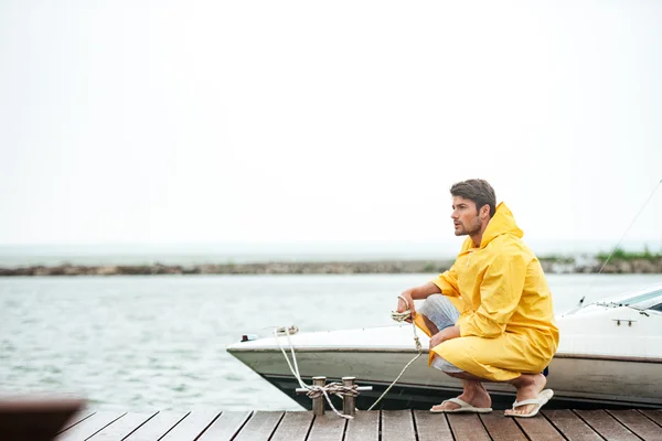 Sailor in yellow cloak holding rope at the pier — Stock Photo, Image