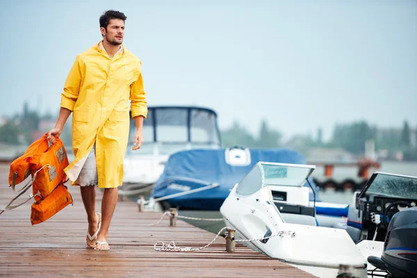 Marinaio in mantello giallo al molo con giubbotto salvagente — Foto Stock