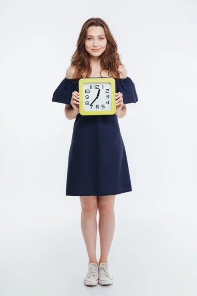 Full length of smiling beautiful woman standing and holding clock — Stock Photo, Image