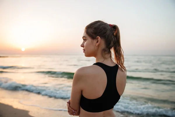 Jovem descansando depois de fazer jogging treinamento na praia ao pôr do sol — Fotografia de Stock