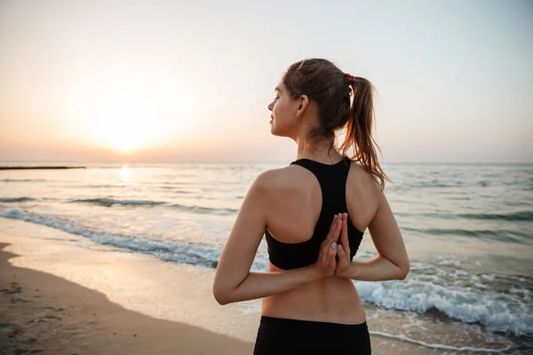 Bella giovane donna che si estende durante lo yoga sulla spiaggia — Foto Stock