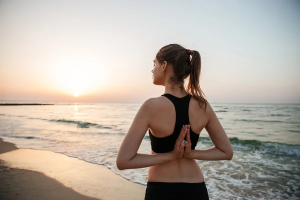 Hermosa joven estiramiento durante yoga en la playa — Stockfoto