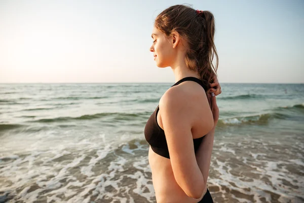 Vista lateral de una mujer estirándose durante el yoga en la playa — Foto de Stock
