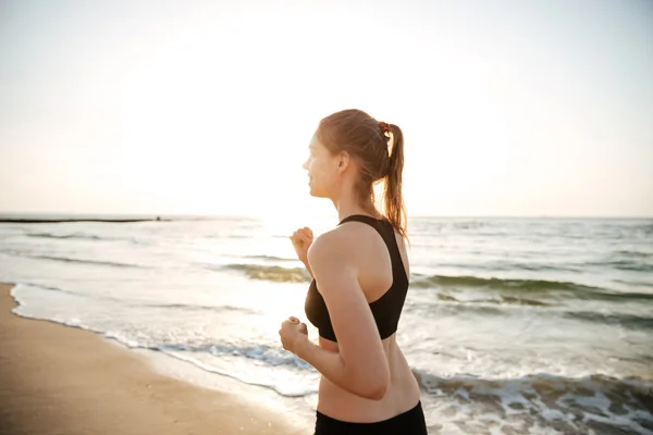Mujer joven y saludable corriendo en la playa — Foto de Stock