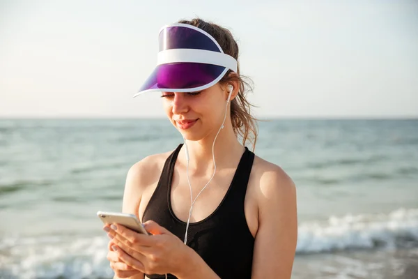 Fitness-Frau ruht sich am Strand aus und hört Musik mit Handy — Stockfoto
