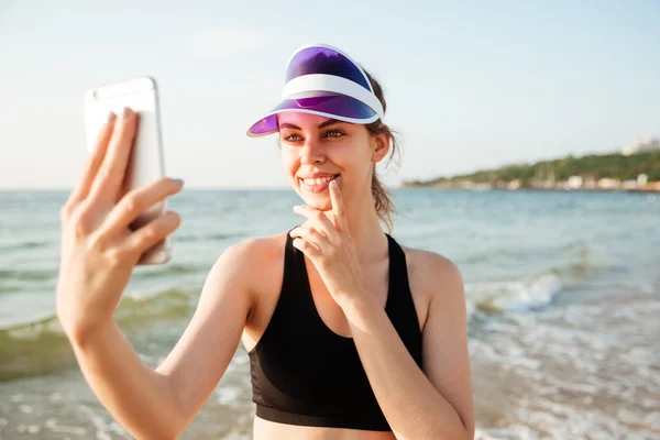 Uśmiechnięta kobieta sportowy biorąc selfie korzystanie ze smartfona na plaży — Zdjęcie stockowe
