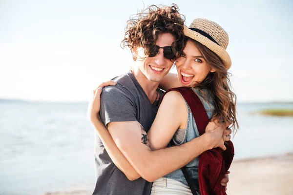 Casal alegre de pé e abraçando na praia — Fotografia de Stock