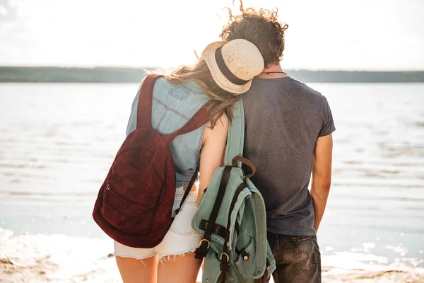 Молода пара, стоячи позаду, обіймає і дивиться на узбережжя — стокове фото