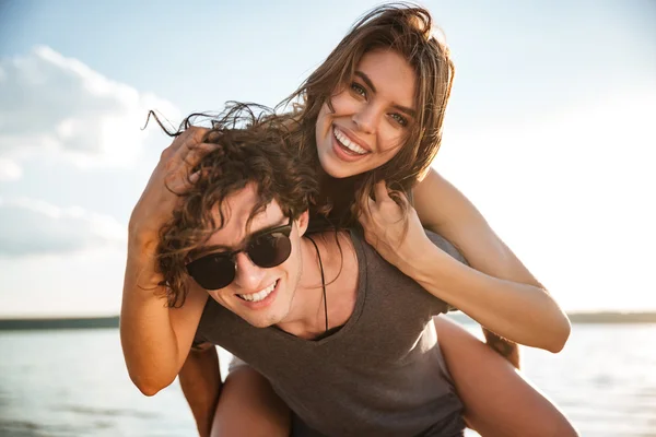 Jovem casal feliz piggyback na praia — Fotografia de Stock