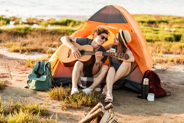 Man speel gitaar en zit op de camping tent — Stockfoto