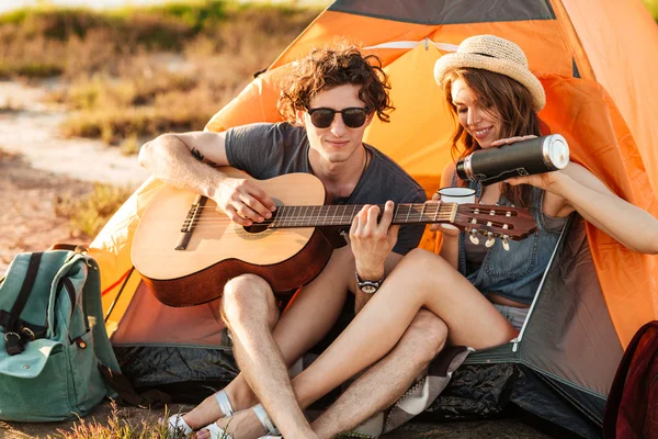 Porträt eines Mannes, der beim Zelten für seine Freundin Gitarre spielt — Stockfoto