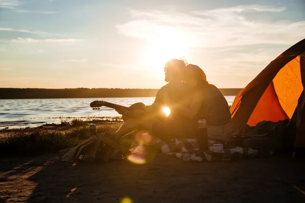 Silhouet van het paar in de buurt van toeristische tent zitten en knuffelen — Stockfoto