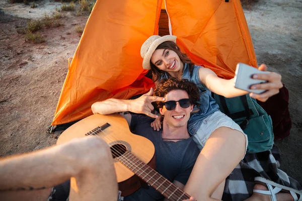 Felice giovane coppia facendo selfie con smartphone da un lago — Foto Stock
