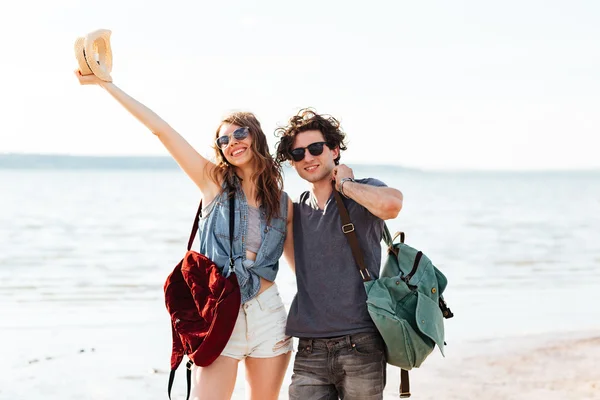 Feliz joven pareja de pie en la playa y abrazándose — Foto de Stock