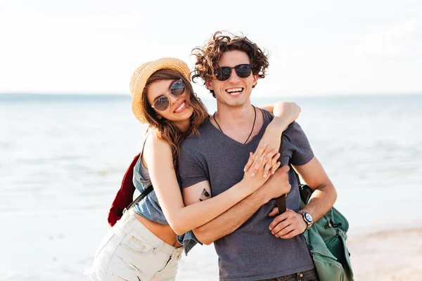 Hipster ευτυχισμένο ζευγάρι στέκεται στην παραλία και αγκαλιάζει — Φωτογραφία Αρχείου