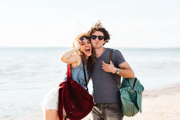 Feliz pareja hipster de pie en la playa y abrazándose — Foto de Stock