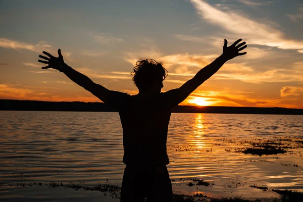 Happy Man Silhouette mit den Händen nach oben auf dem Sonnenuntergang Hintergrund — Stockfoto