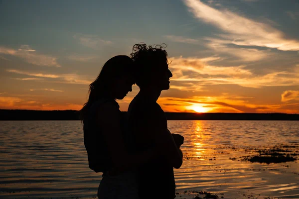 Silhouette of couple hugging near the sea on sunset — Stock Photo, Image