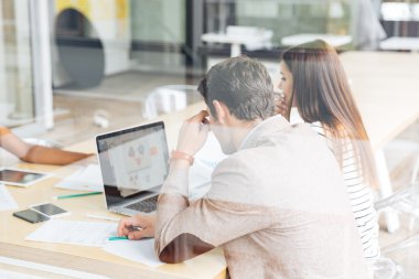 Yeni fikirleri tartışan ve dizüstü bilgisayar kullanan bir grup iş adamı