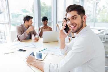 Neşeli işadamı oturma ve ofiste meslektaşları ile çalışan