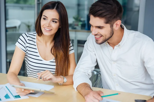 Cheeful ung man och kvinna med tabletten i office — Stockfoto