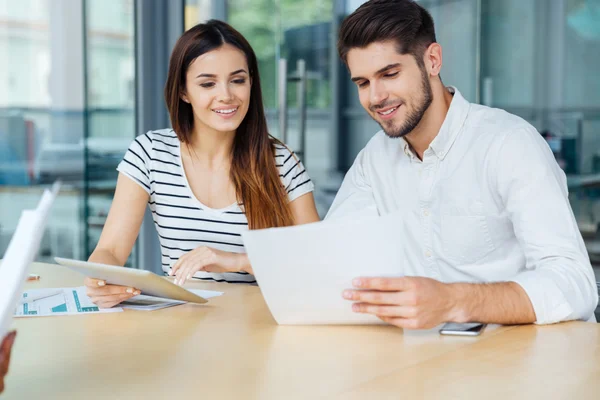 Χαμογελαστός, νεαρό ζευγάρι με tablet κάθεται και εργάζεται στο γραφείο — Φωτογραφία Αρχείου