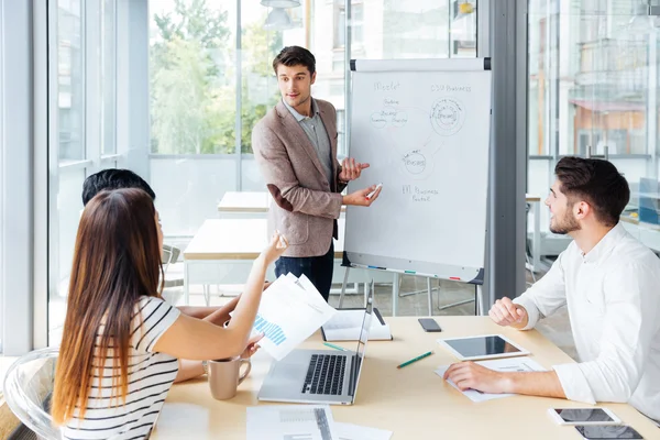 Pewny biznesmen dając prezentację za pomocą flipchart w biurze — Zdjęcie stockowe