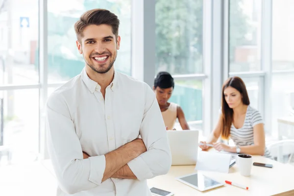 Leende affärsman står med armarna korsade i office — Stockfoto