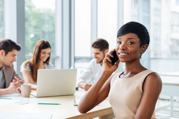 Zakenvrouw praten op mobiele telefoon tijdens het werken met business team — Stockfoto