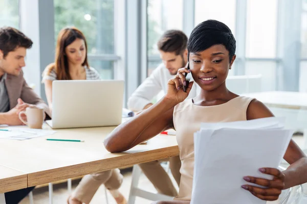 Empresária trabalhando com documentos e conversando no celular — Fotografia de Stock