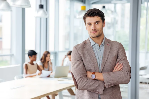 Successful businessman standing with arms crossed in office — Stock Photo, Image
