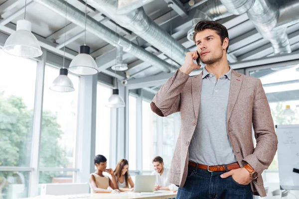 Uomo d'affari serio in piedi e parlando sul telefono cellulare in ufficio — Foto Stock