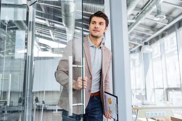 Businessman with clipboard entering the door in office — Stock Photo, Image