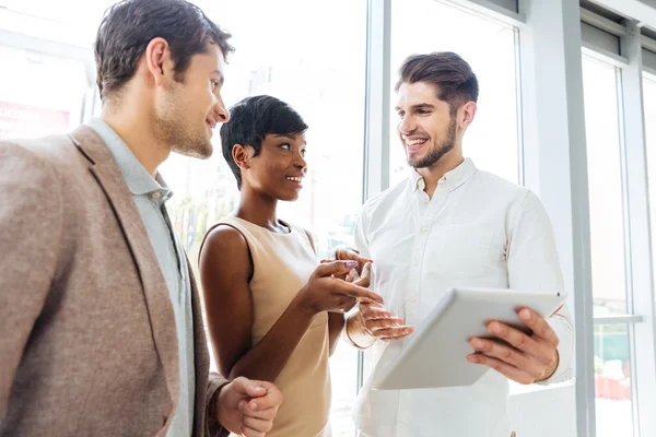 Les gens d'affaires parlent et utilisent la tablette ensemble dans le bureau — Photo