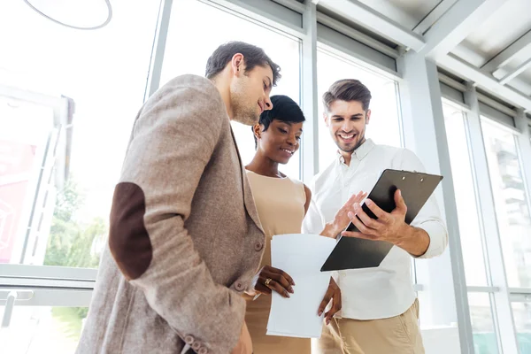 Tres empresarios felices revisando documentos juntos en la oficina — Foto de Stock