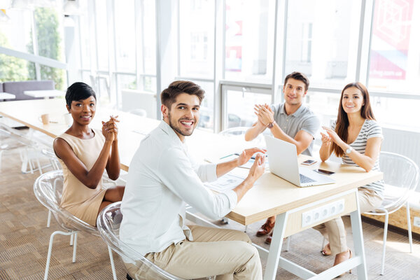 Business people sitting and clapping hands during presentation in office