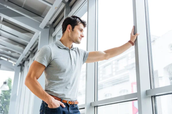 Thoughtful man standing and looking at the window — Stock Photo, Image