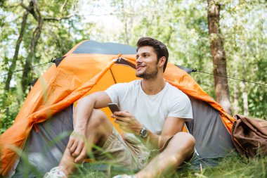 Adam turist turistik orman çadırda oturan smartphone kullanarak